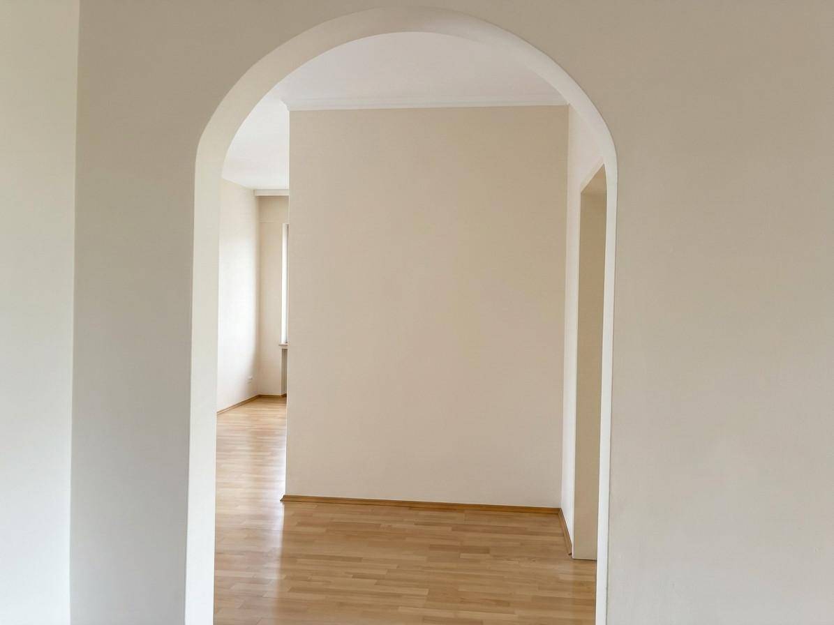 Heller Durchgang mit einem eleganten Bogen, der zu einem weiteren Zimmer führt.