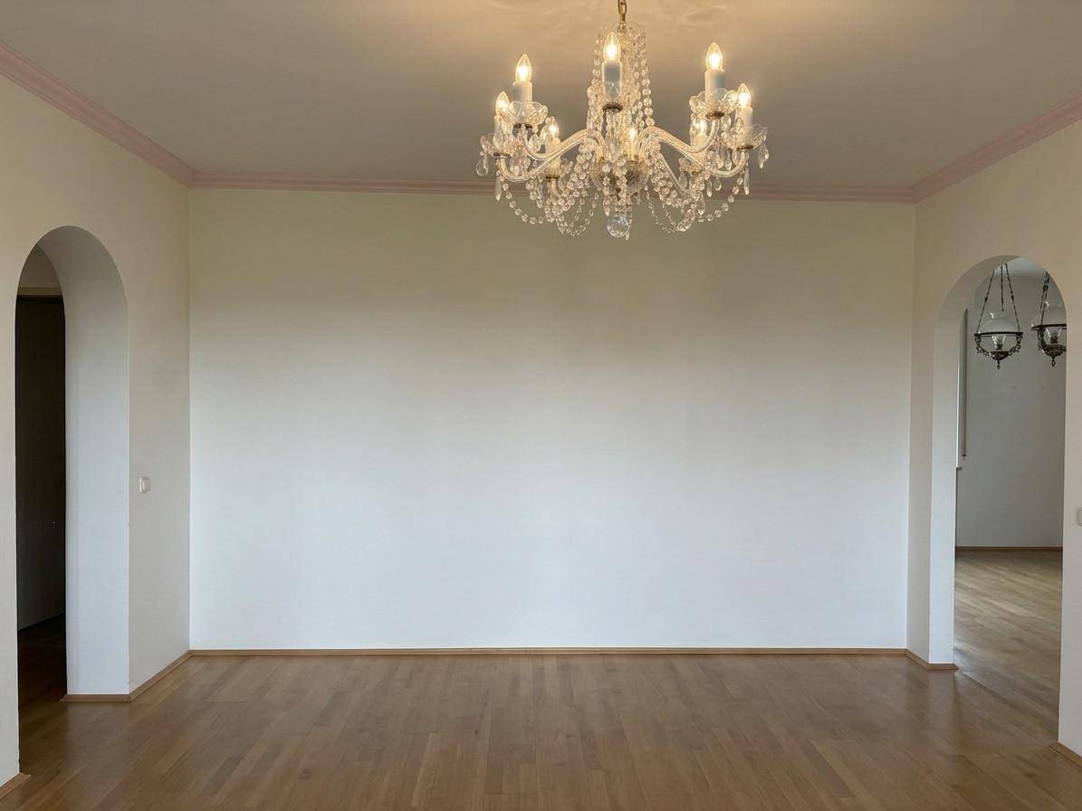 Helles Zimmer mit Parkettboden, Kronleuchter und zwei eleganten Bogendurchgängen.