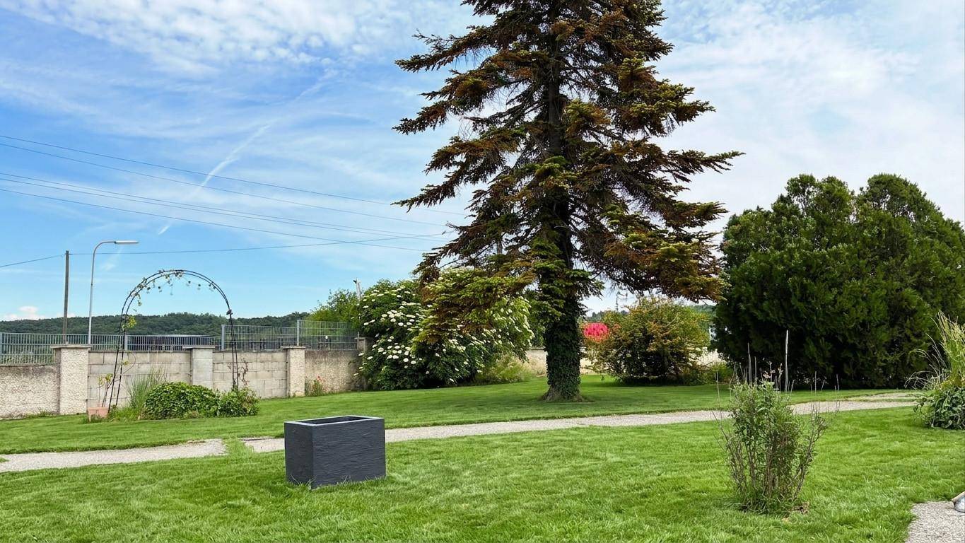 Großer Gartenbereich mit altem Baum, Rasenfläche und weitem Blick in die Landschaft.