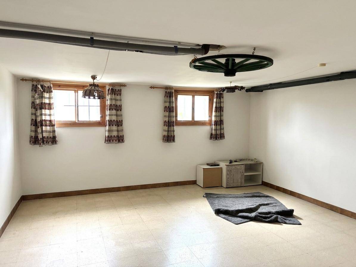 Geräumiger Kellerraum mit kleinen Fenstern, Teppich und rustikaler Deckenleuchte.