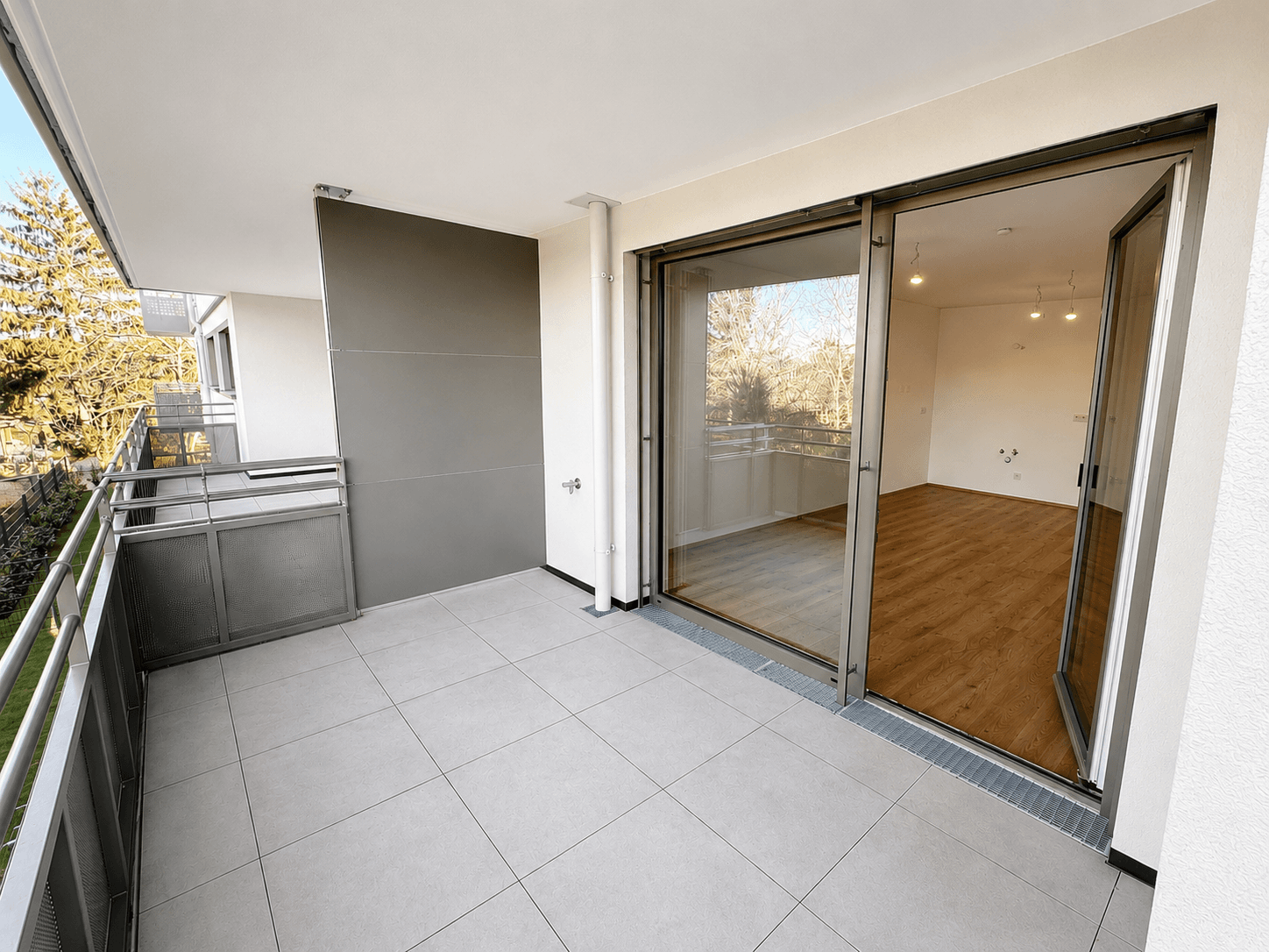 Geräumiger Balkon mit Fliesenboden und Blick auf die Umgebung, zugänglich vom Wohnbereich.