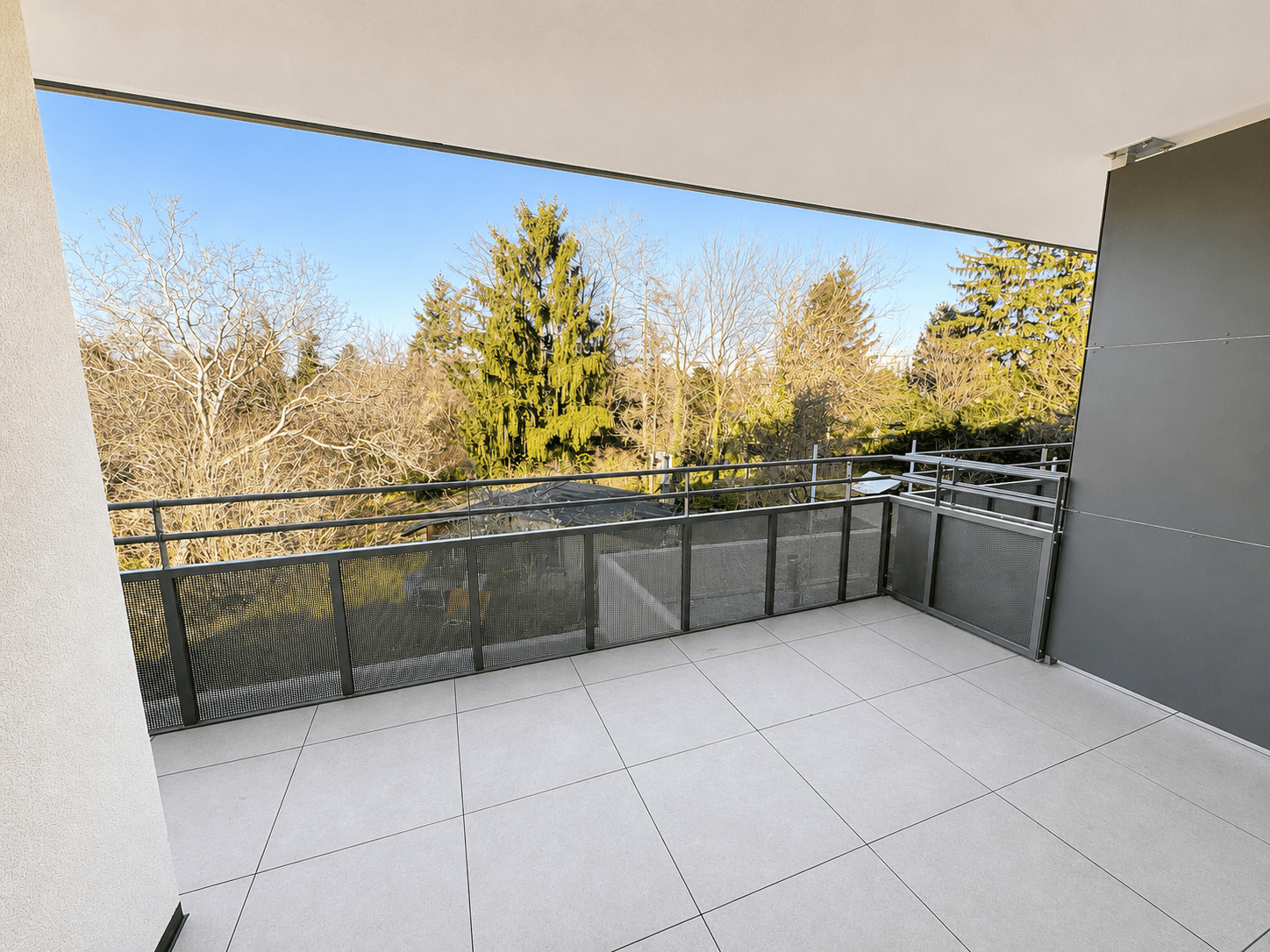 Breiter Balkon mit moderner Metallbrüstung und weitem Blick ins Grüne.