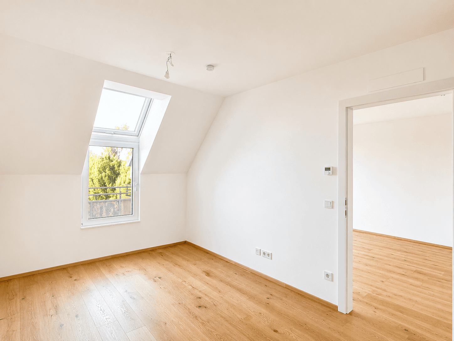 Helles Zimmer im Dachgeschoss mit Holzboden und großem Dachfenster, ideal als Schlafzimmer oder Büro.