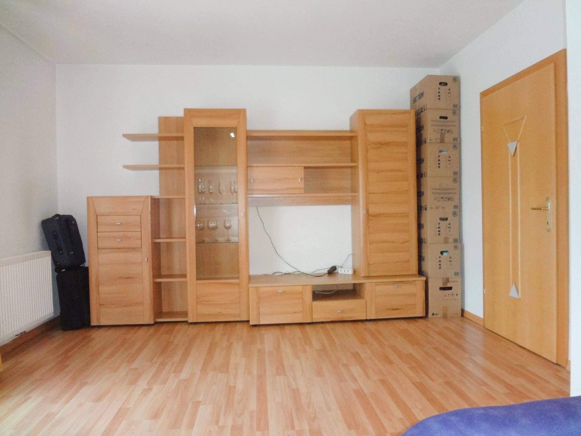 Wohnzimmer mit Laminatboden und großer Holzschrankwand, bereit zur Einrichtung.