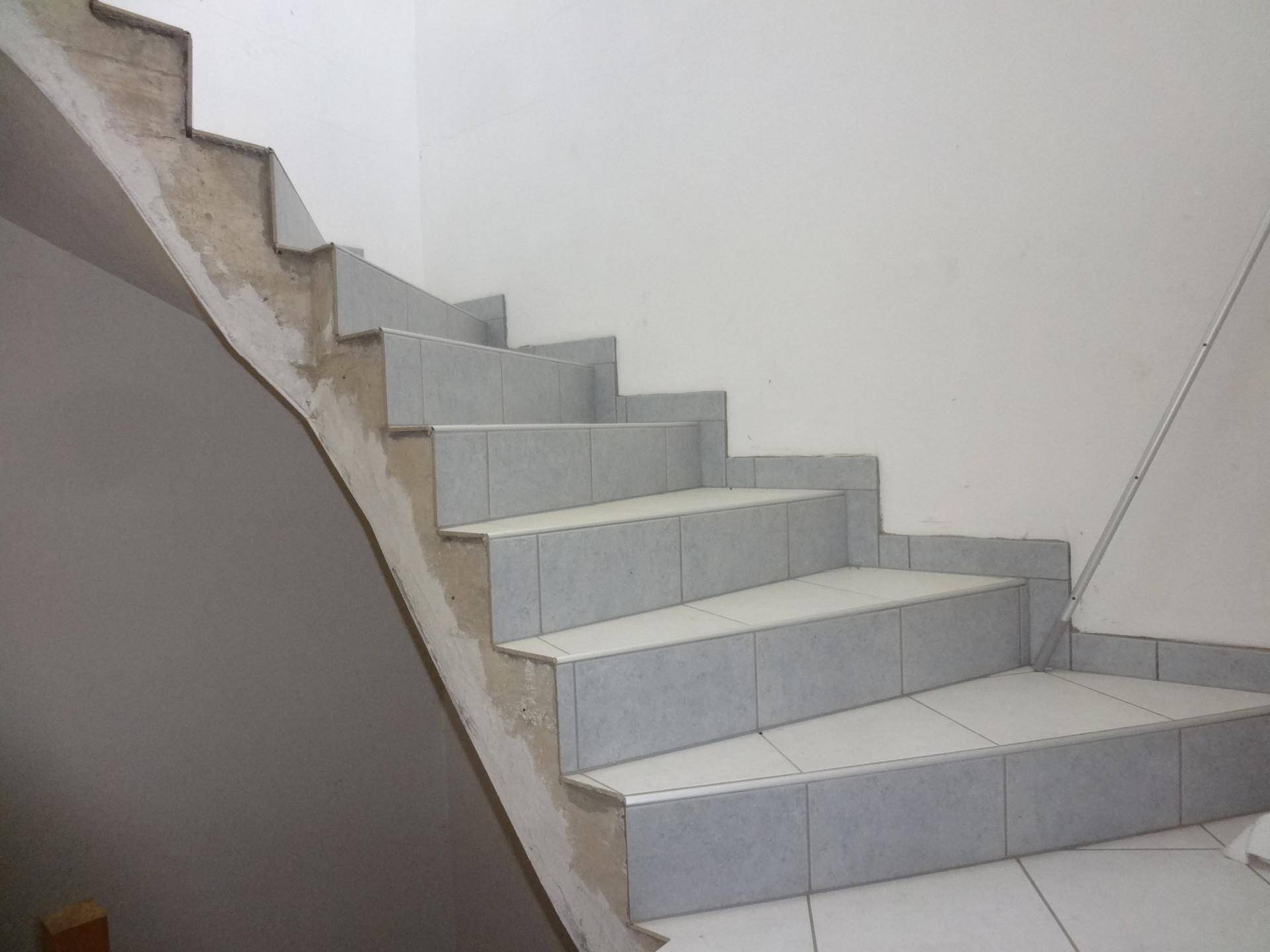Treppenhaus mit gefliesten Stufen und unfertigen Wänden, die auf Renovierung warten.