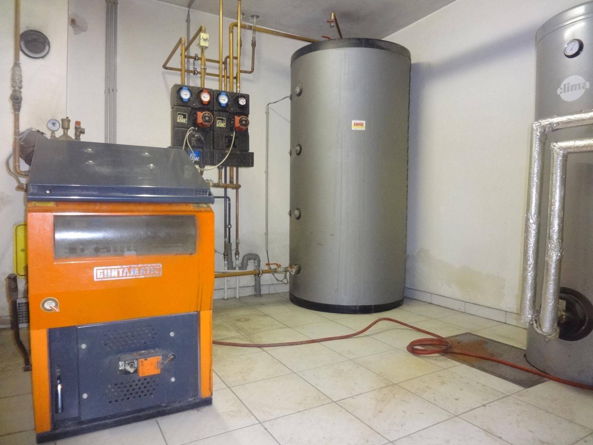 Heizungsraum mit großem Warmwasserspeicher und Heizkessel.