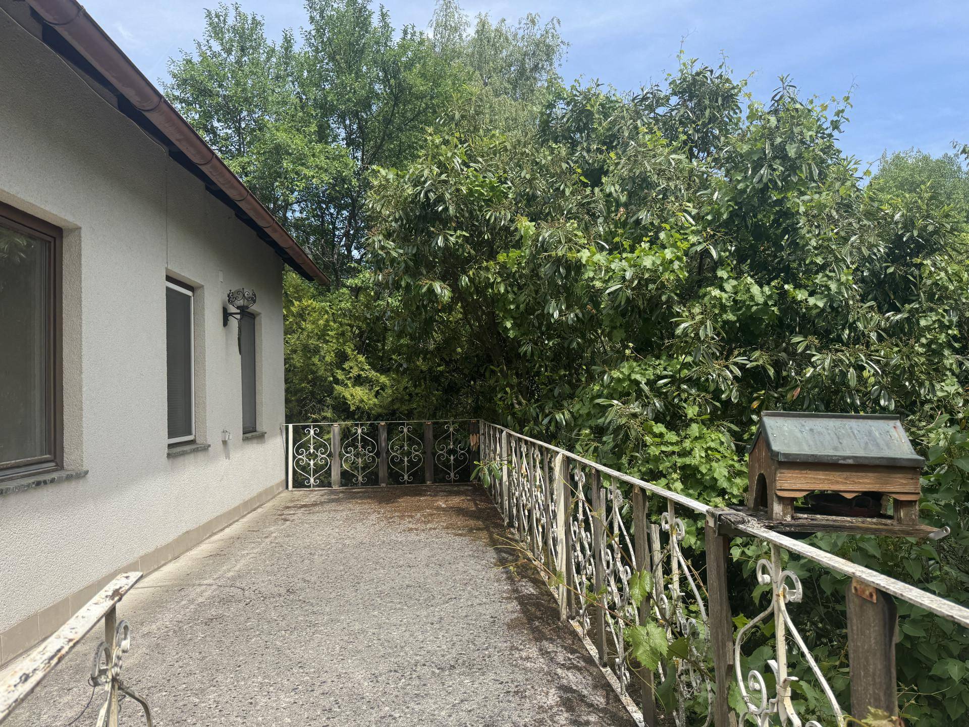 Alter Balkon mit schmiedeeisernem Geländer und einem weiten Blick ins Grüne.