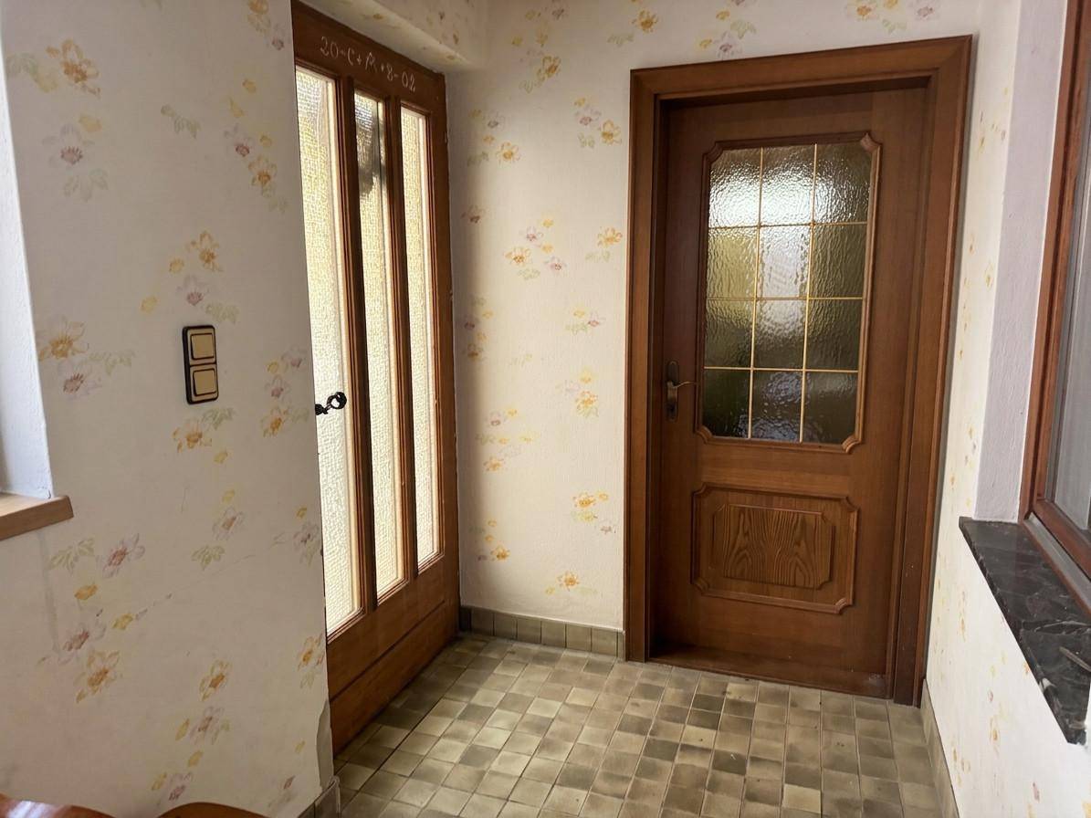 Eingangsbereich mit gemusterten Tapeten, Holztüren und einem gefliesten Boden im traditionellen Stil.