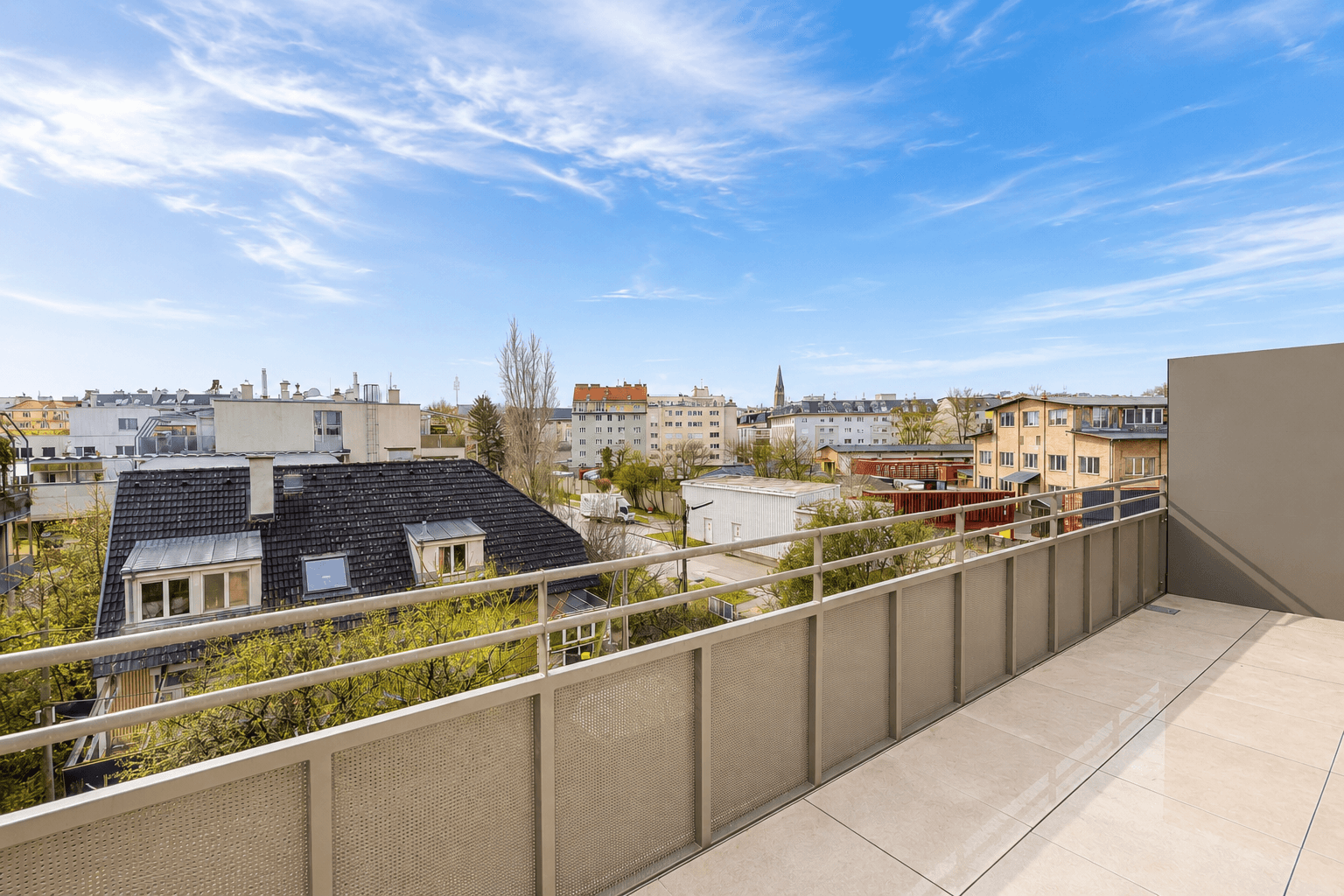 Geräumiger Balkon mit Fliesenboden und weitem Blick über die Stadt und umliegende Gebäude.