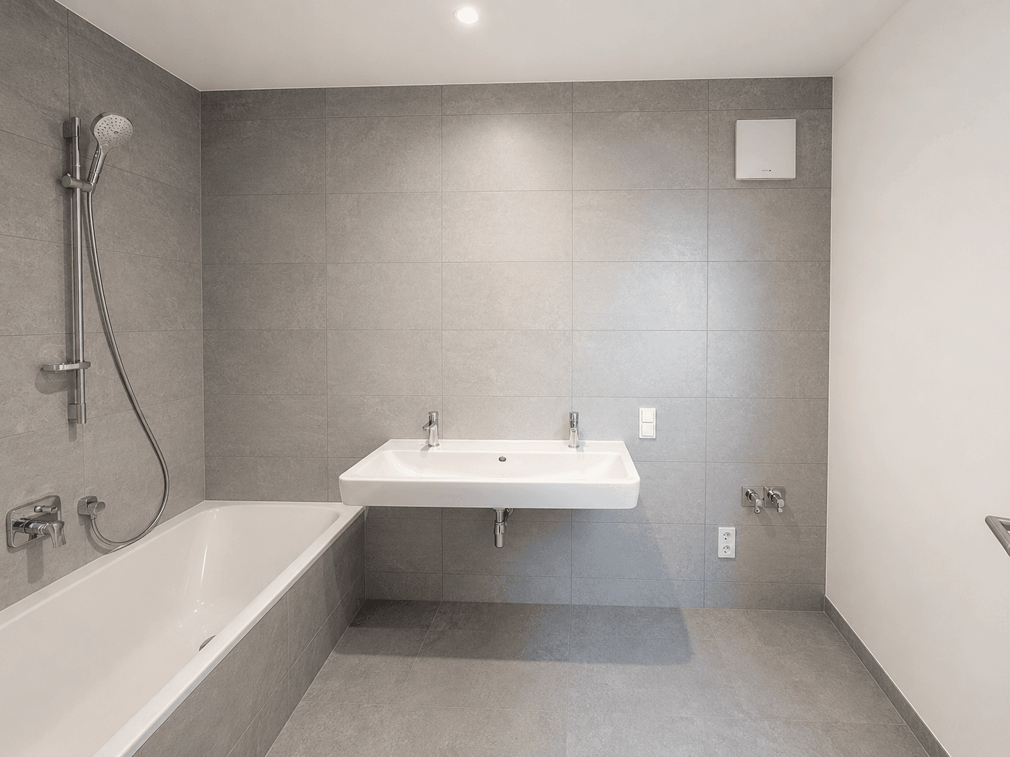 Modernes Badezimmer mit grauen Fliesen, Badewanne und Doppelwaschbecken.
