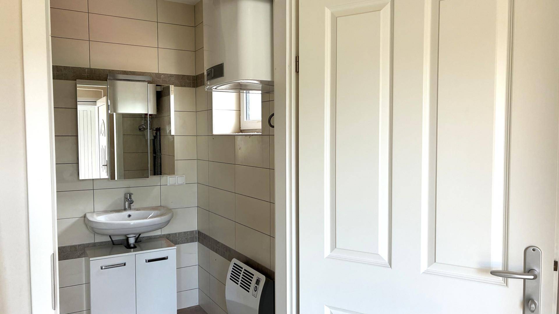 Helles Badezimmer mit Fliesen, Einzelwaschbecken und Spiegelschrank.
