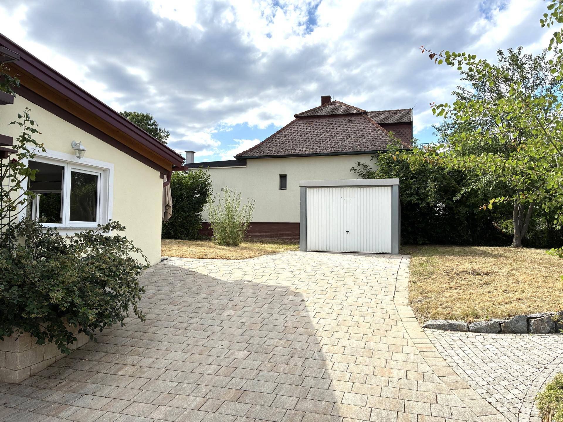 Gepflasterte Einfahrt führt zu einer freistehenden Garage neben dem Haus.