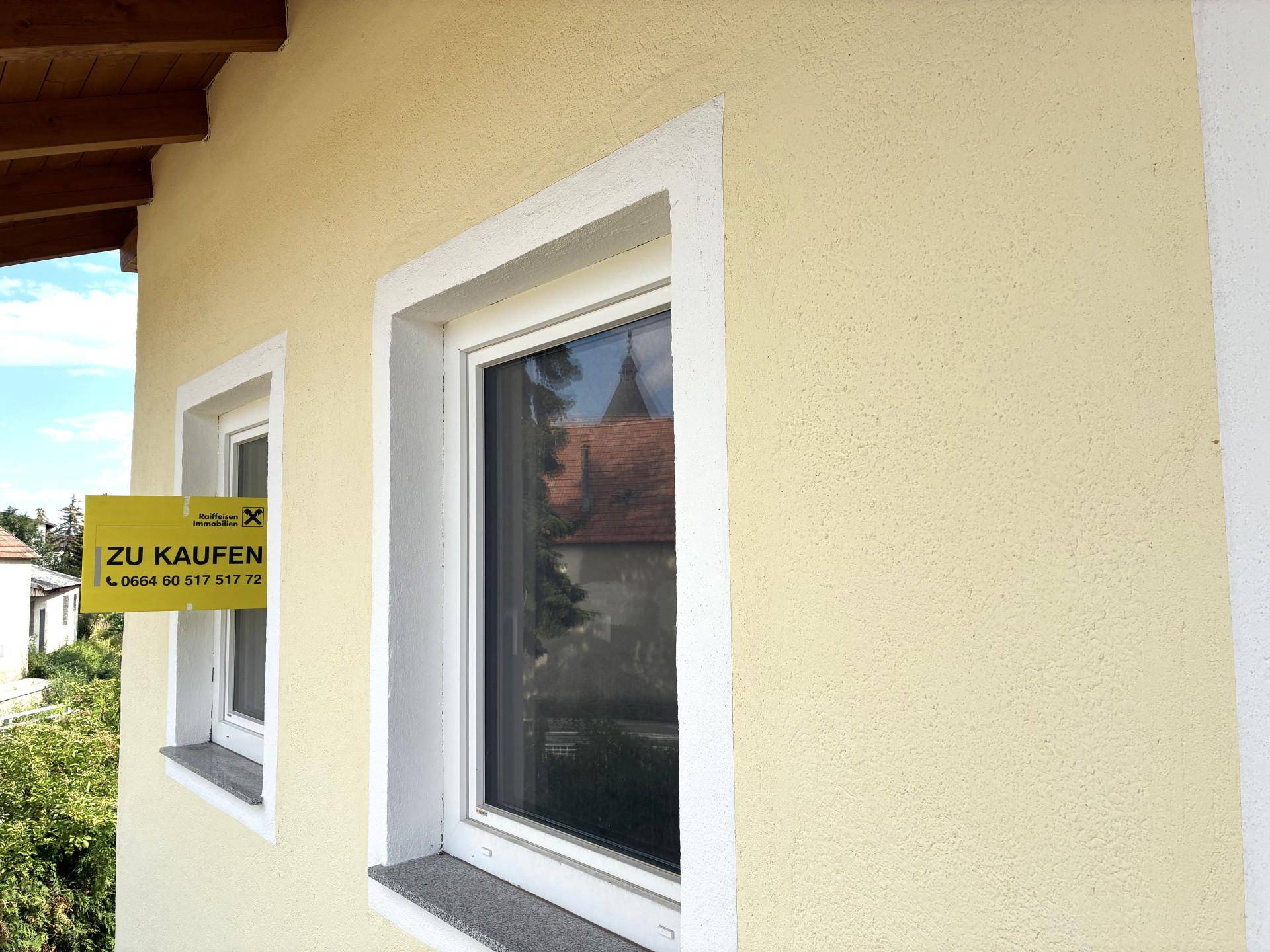 Nahaufnahme eines Fensters an der Hausfassade mit einem "Zu Kaufen" Schild.