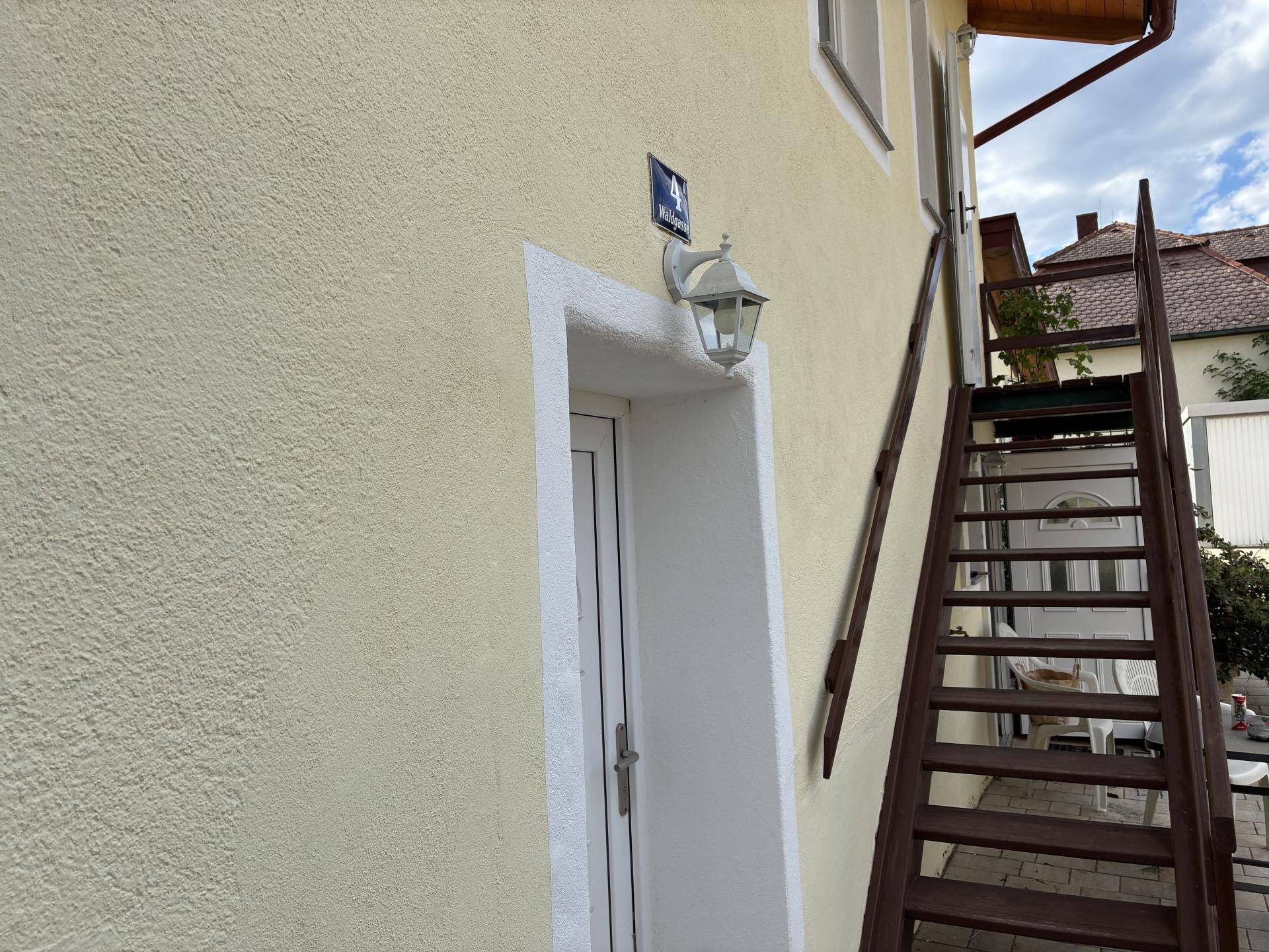 Eingangsbereich des Hauses mit Außentreppe und klassischer Wandleuchte.