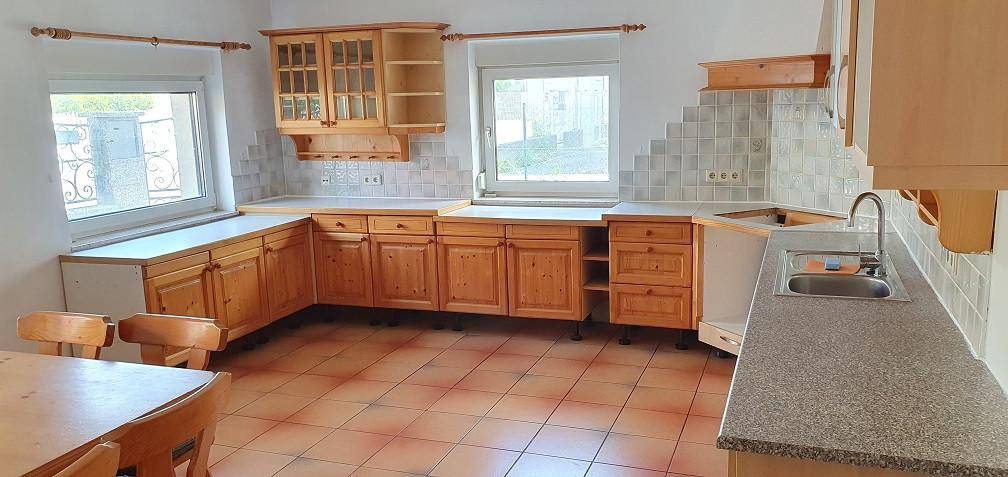 Küche im Landhausstil mit Holzschränken, Fliesenboden und viel Stauraum.