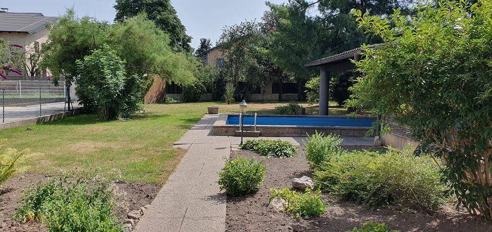 Gepflegter Gartenbereich mit Rasenfläche, Bäumen und einem kleinen Pool.