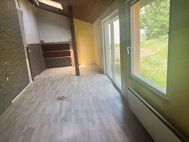 Heller Wohnraum mit neuem Laminatboden und Zugang zum Außenbereich durch große Fenster.