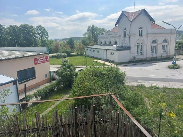 Weitblick über eine grüne Landschaft mit einem historischen Gebäude im Hintergrund unter blauem Himmel.