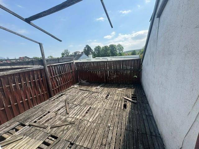 Verfallene Holzterrasse mit kaputten Dielen und Holzzaun, benötigt umfassende Sanierung.