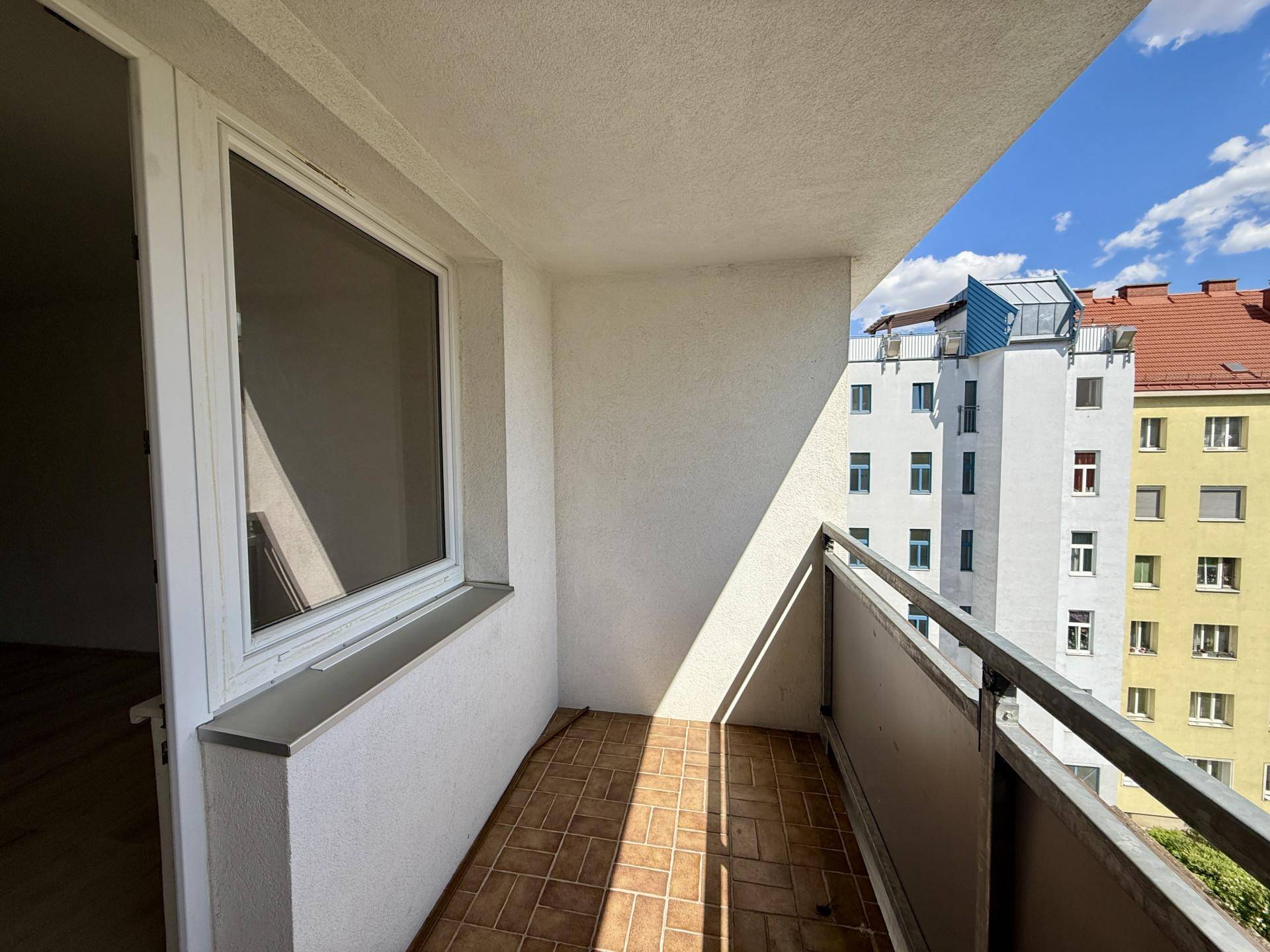 Sonniger Balkon mit Fliesenboden und Blick auf die umliegenden Gebäude.