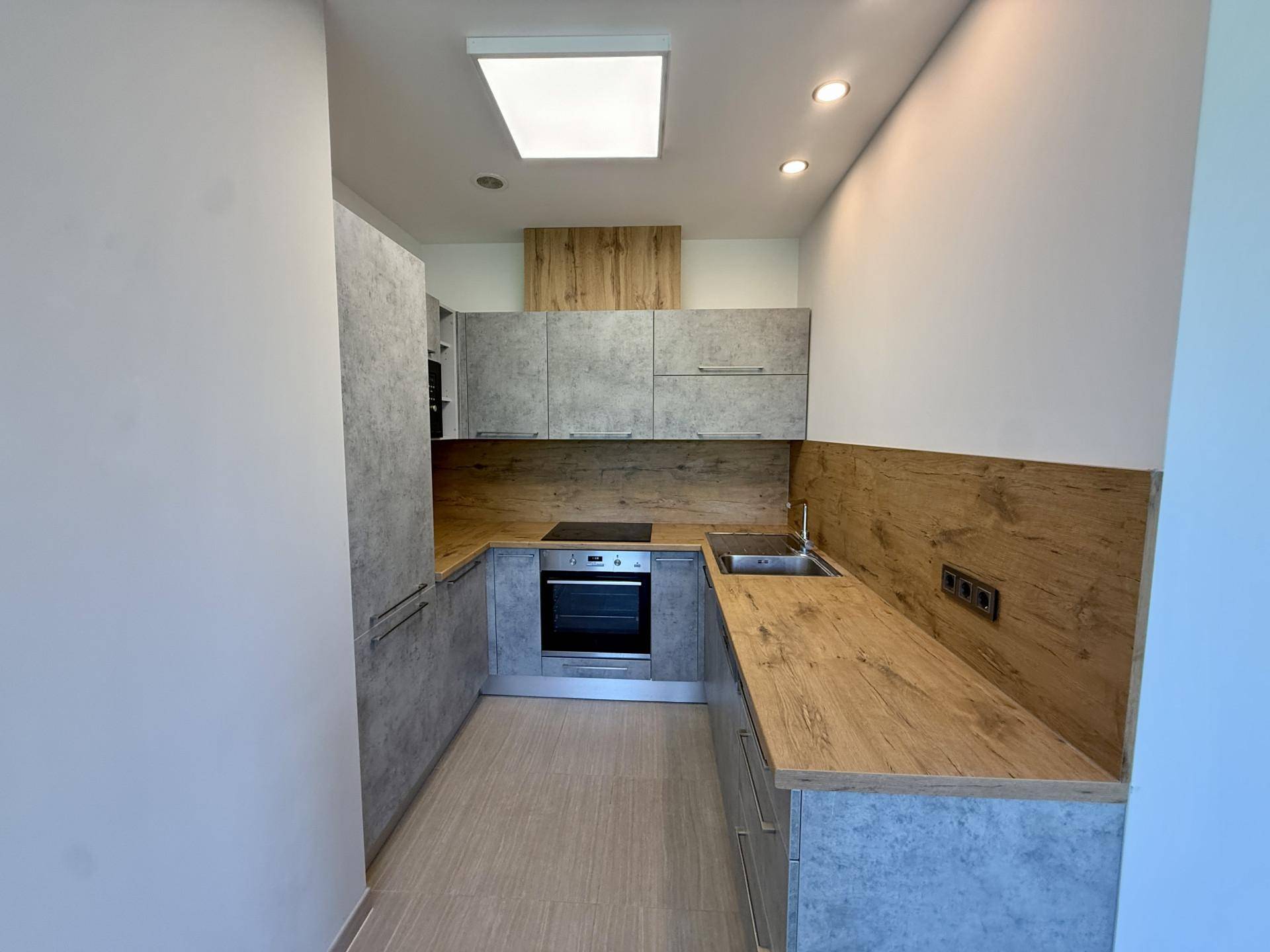 Moderne Küchenzeile mit grauen Fronten, Holz-Arbeitsplatten und integrierten Geräten.