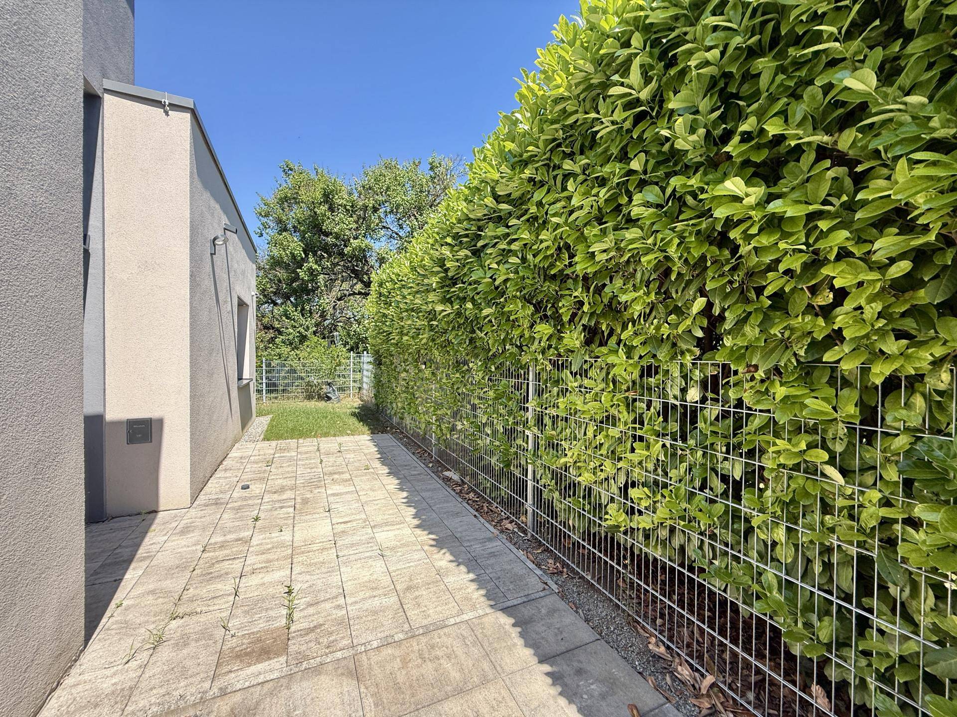 Gepflasterter Weg entlang einer hohen Hecke, die Privatsphäre im Außenbereich bietet.