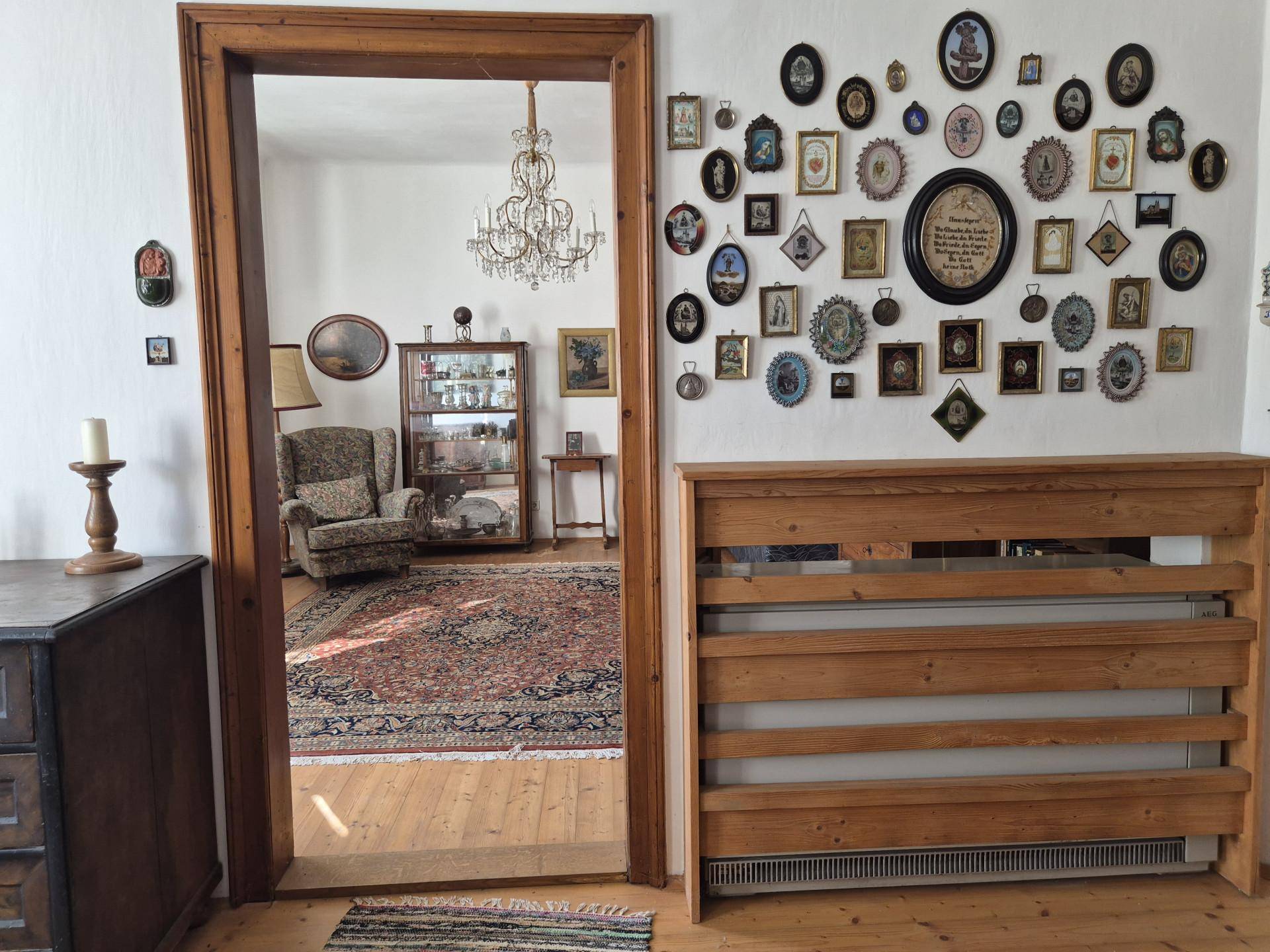 Flur mit Holzboden, traditioneller Wanddekoration und Blick in ein angrenzendes Zimmer.