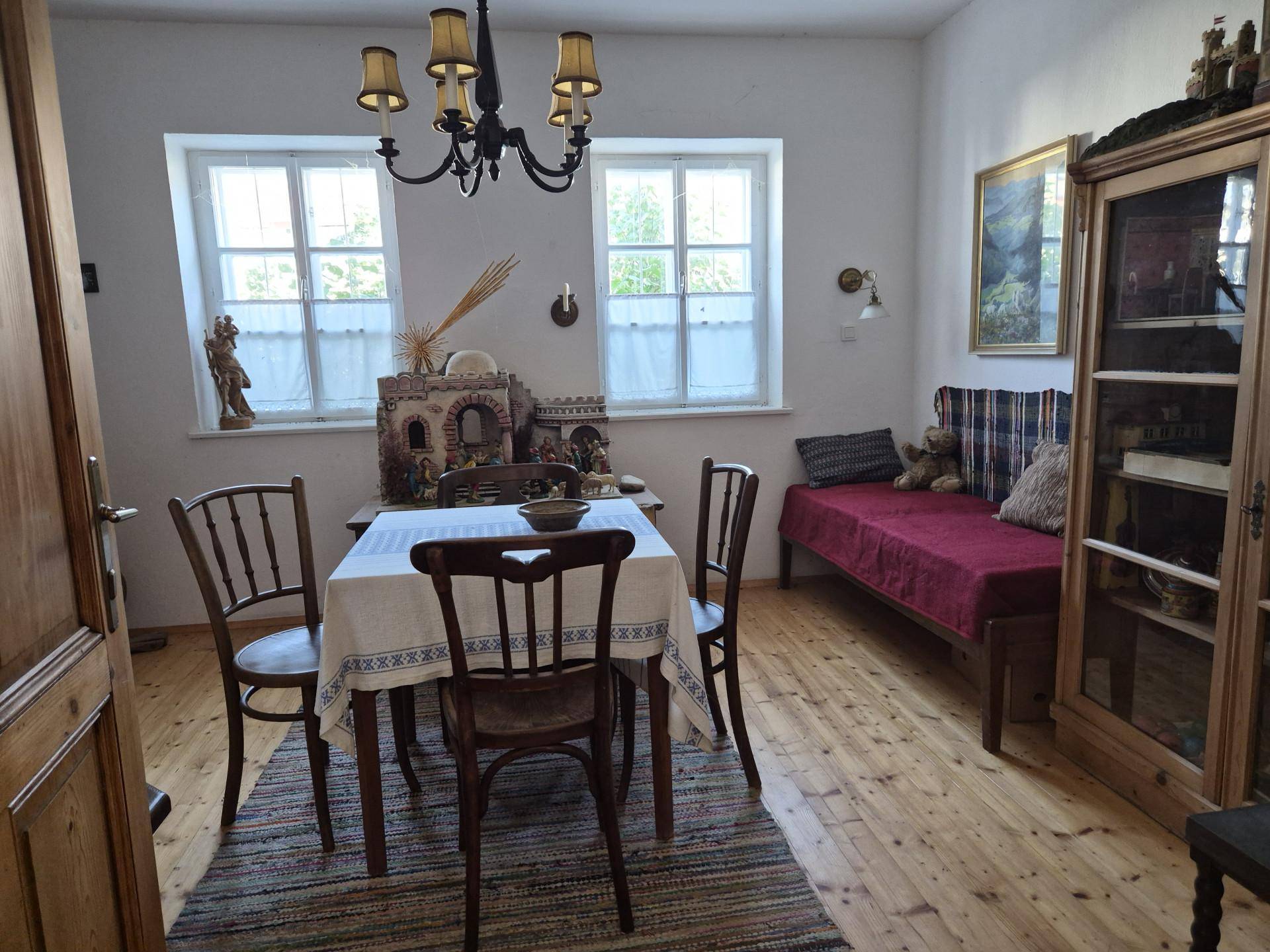 Esszimmer mit Holztisch, Stühlen, Tagesbett und traditionellem Kronleuchter.