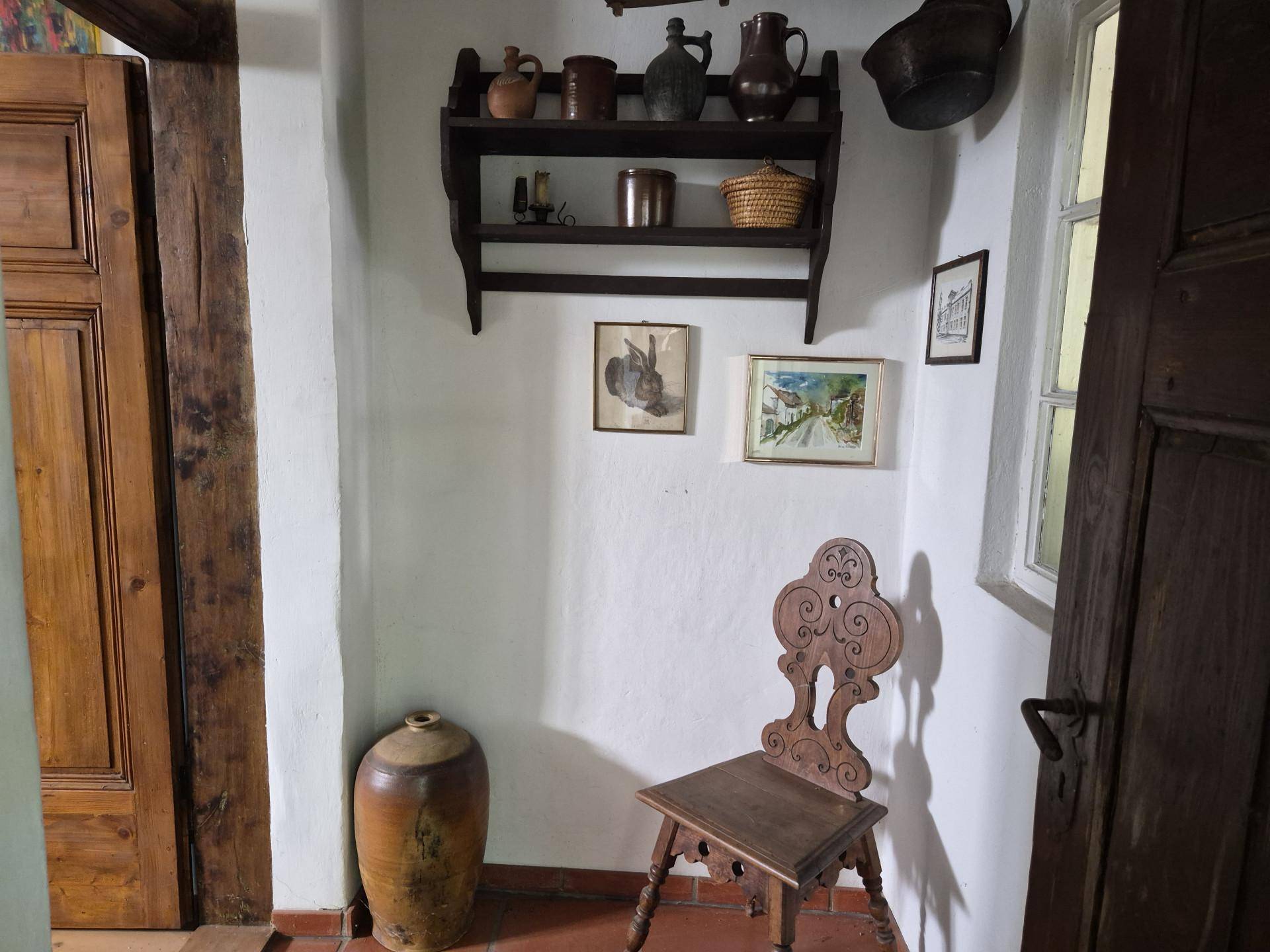 Schmaler Flur mit Terrakottaboden, Holzmöbeln und traditionellen Dekorationen.