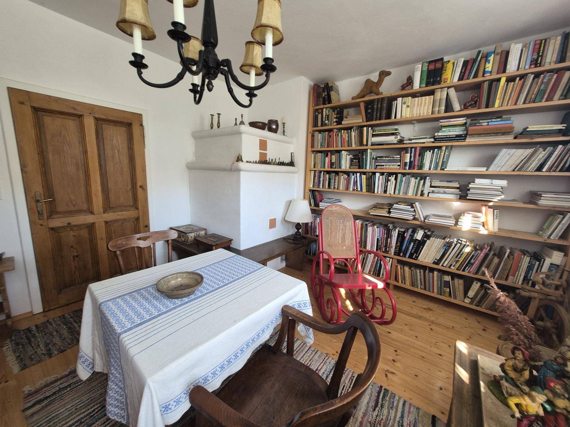Bibliothek mit Bücherregalen, Holzboden und traditionellem Kachelofen.