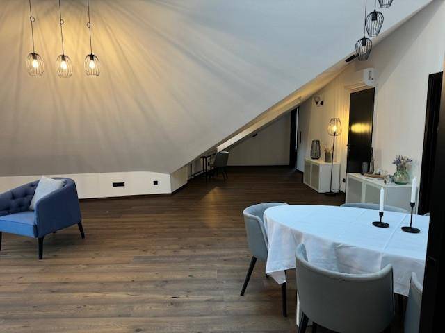 Offener Wohn- und Essbereich im Dachgeschoss mit Holzboden und moderner Einrichtung.