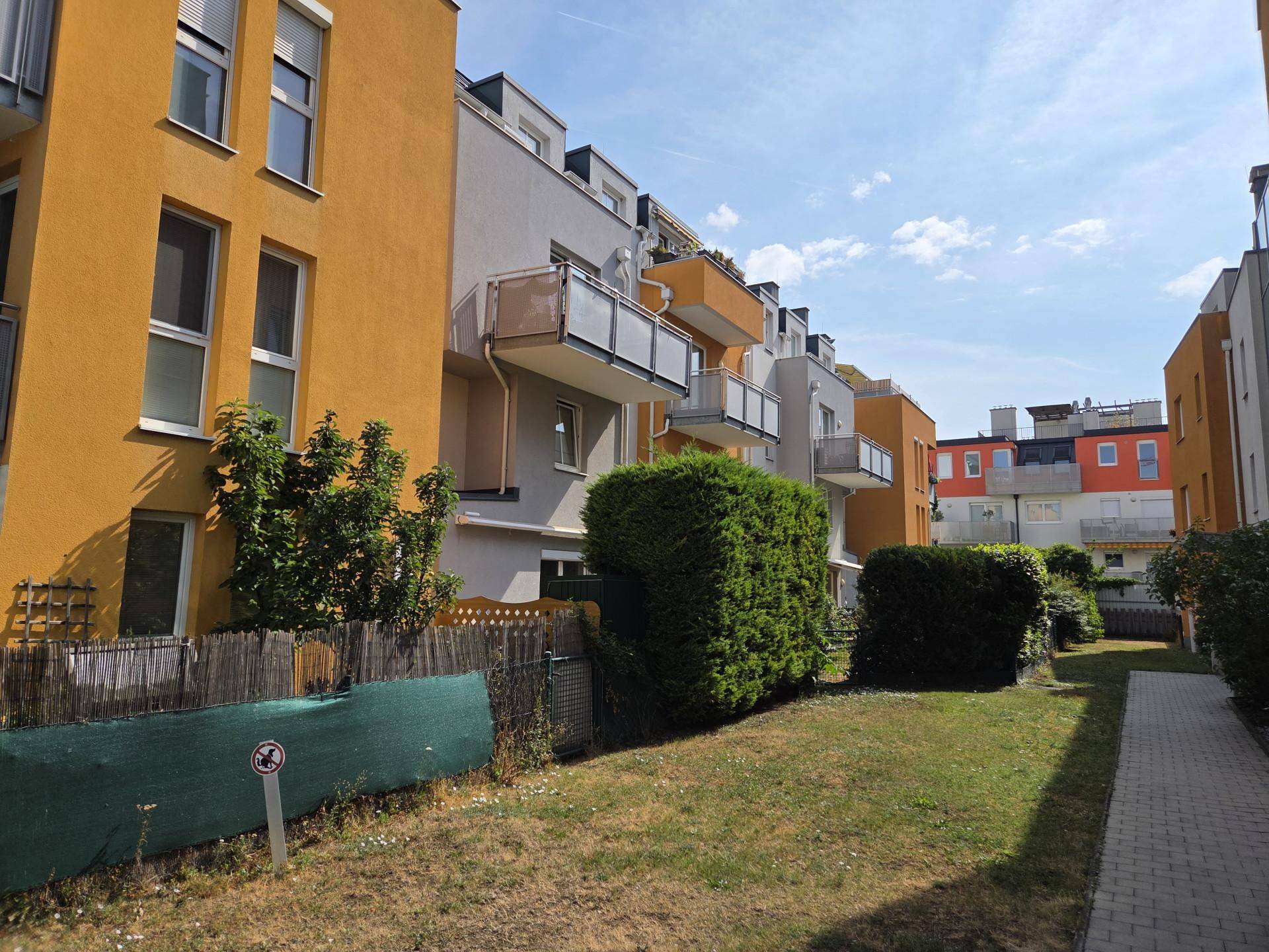 Außenansicht von modernen Wohngebäuden mit farbigen Fassaden und Balkonen in einer Grünanlage.