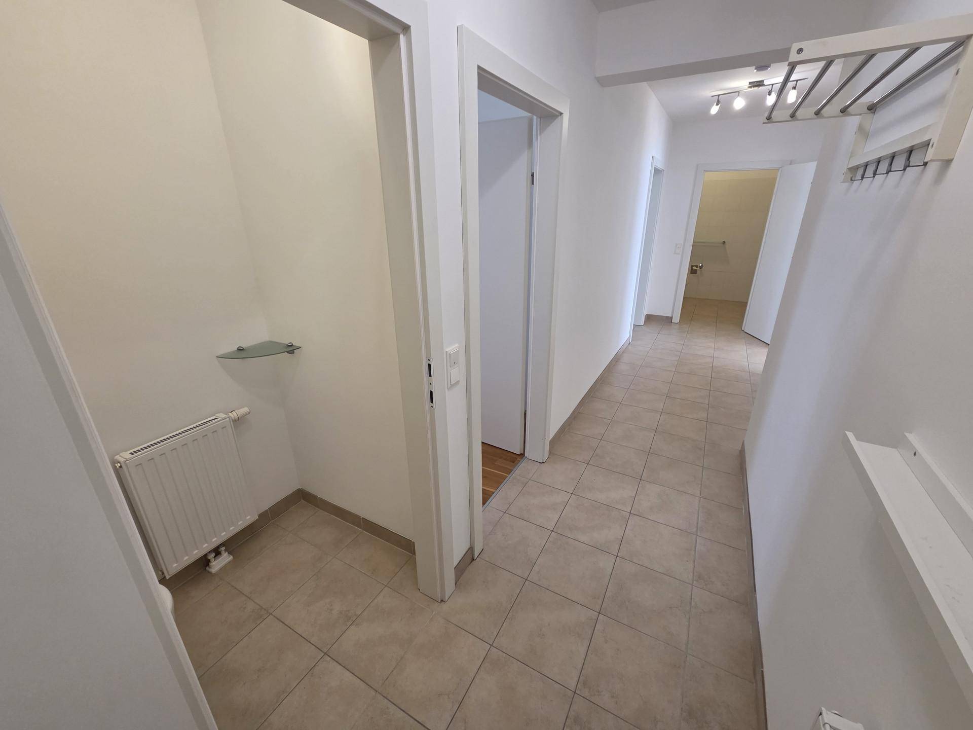 Heller Flur mit Fliesenboden und Zugang zu verschiedenen Zimmern der Wohnung.