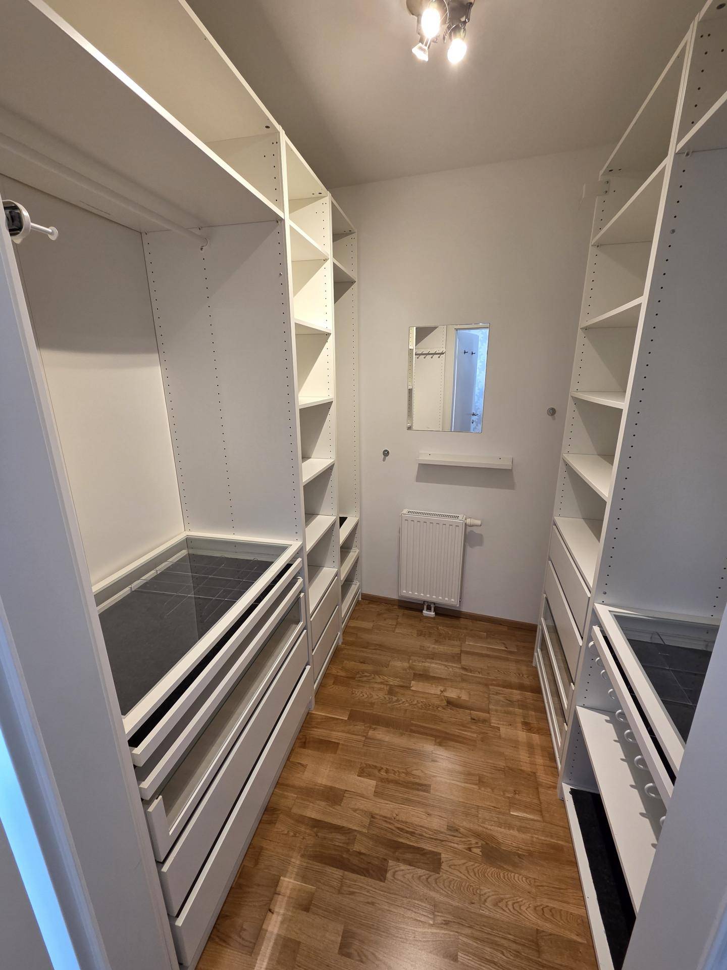 Geräumiger begehbarer Kleiderschrank mit vielen Regalen und Schubladen für optimale Organisation.