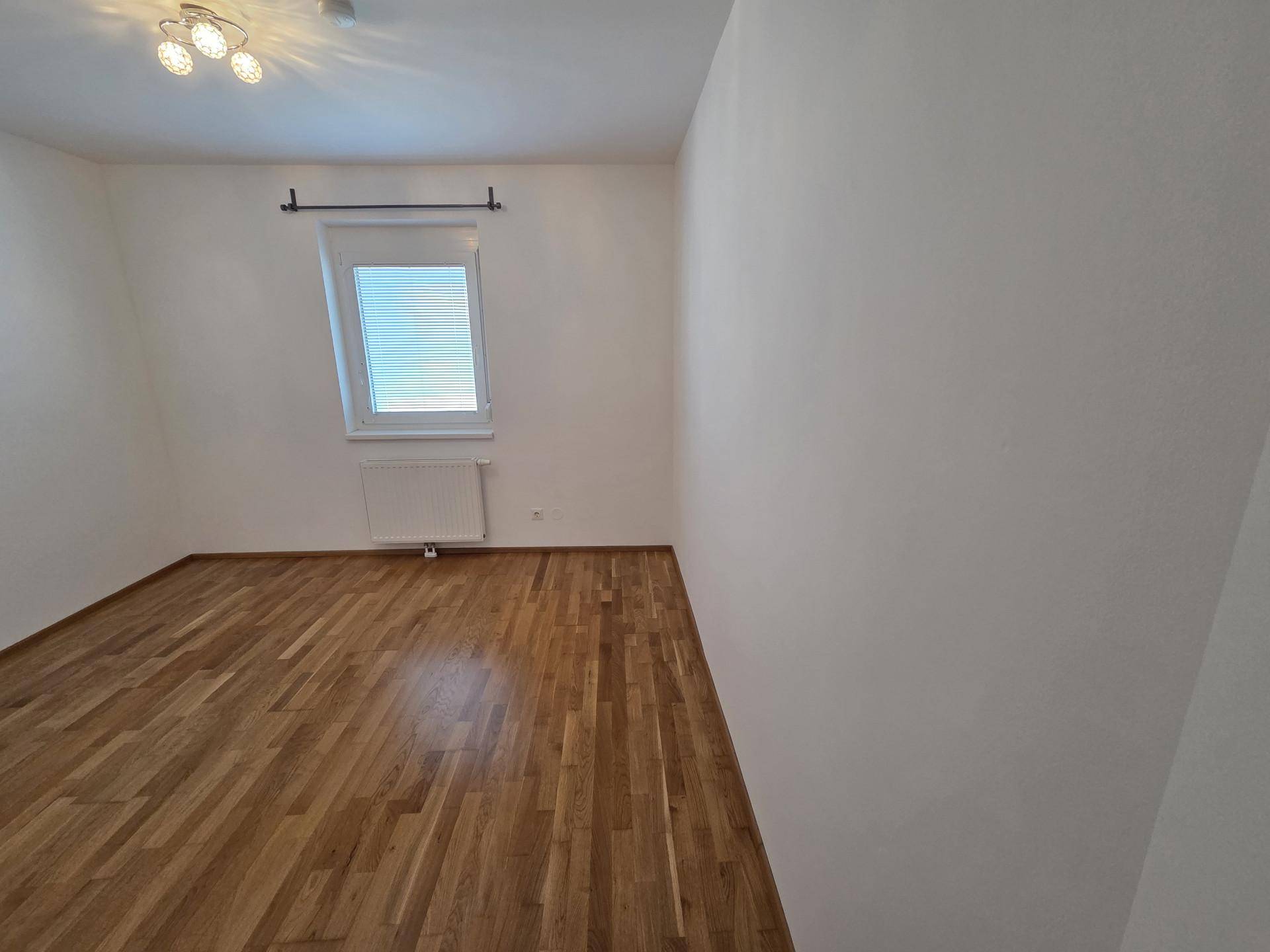 Helles Schlafzimmer mit Holzboden und weiß gestrichenen Wänden, bereit zur individuellen Gestaltung.
