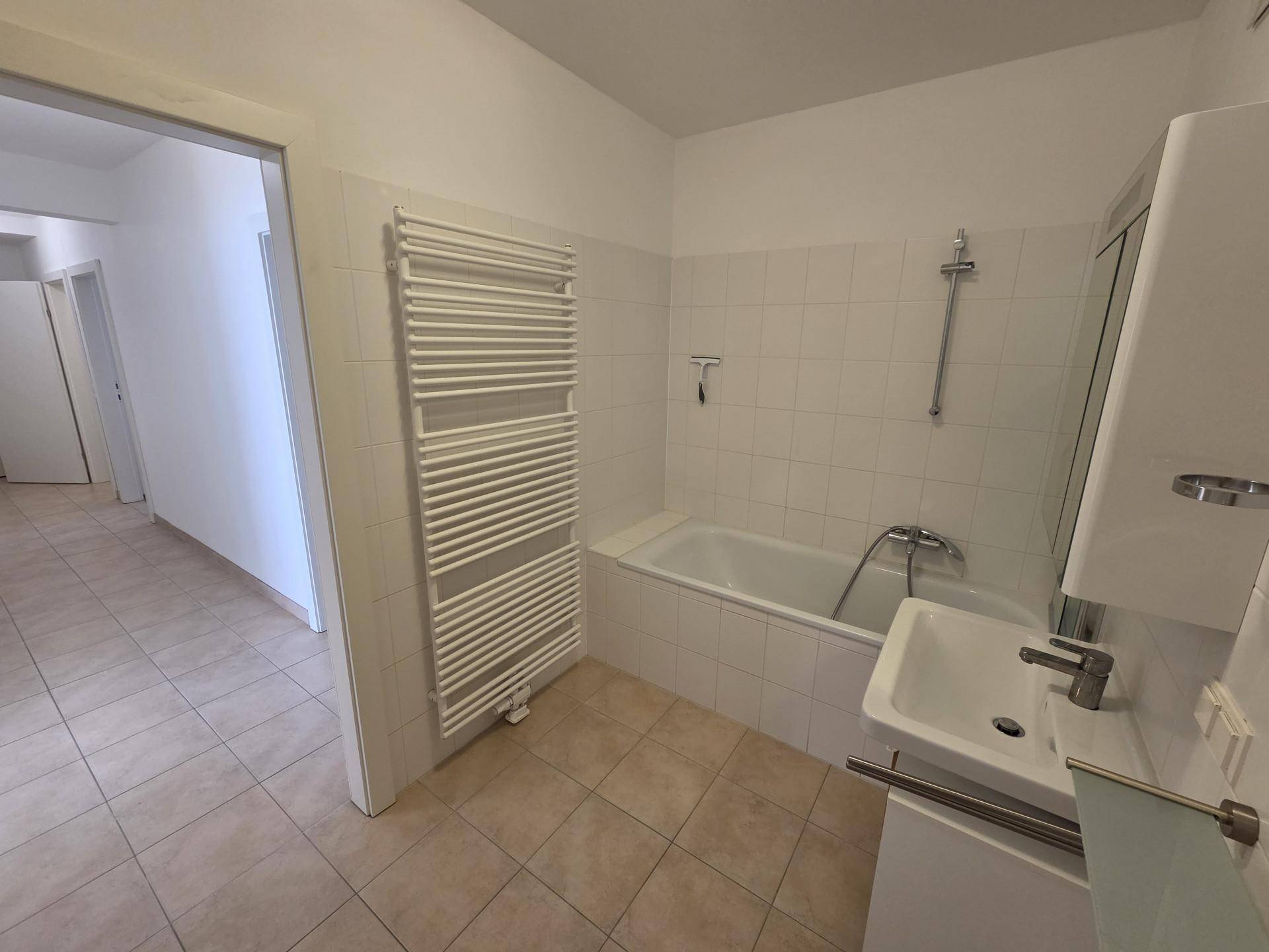 Funktionales Badezimmer mit Badewanne, Waschbecken und praktischem Handtuchheizkörper.