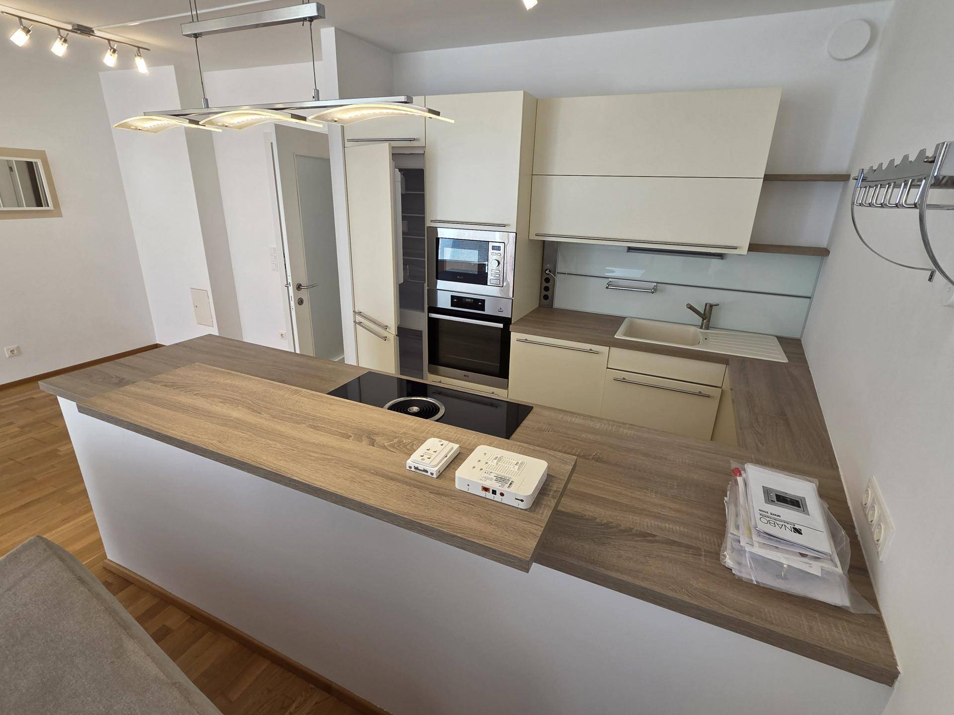 Moderne Einbauküche mit Holz-Arbeitsplatte, Induktionskochfeld und integrierten Geräten.