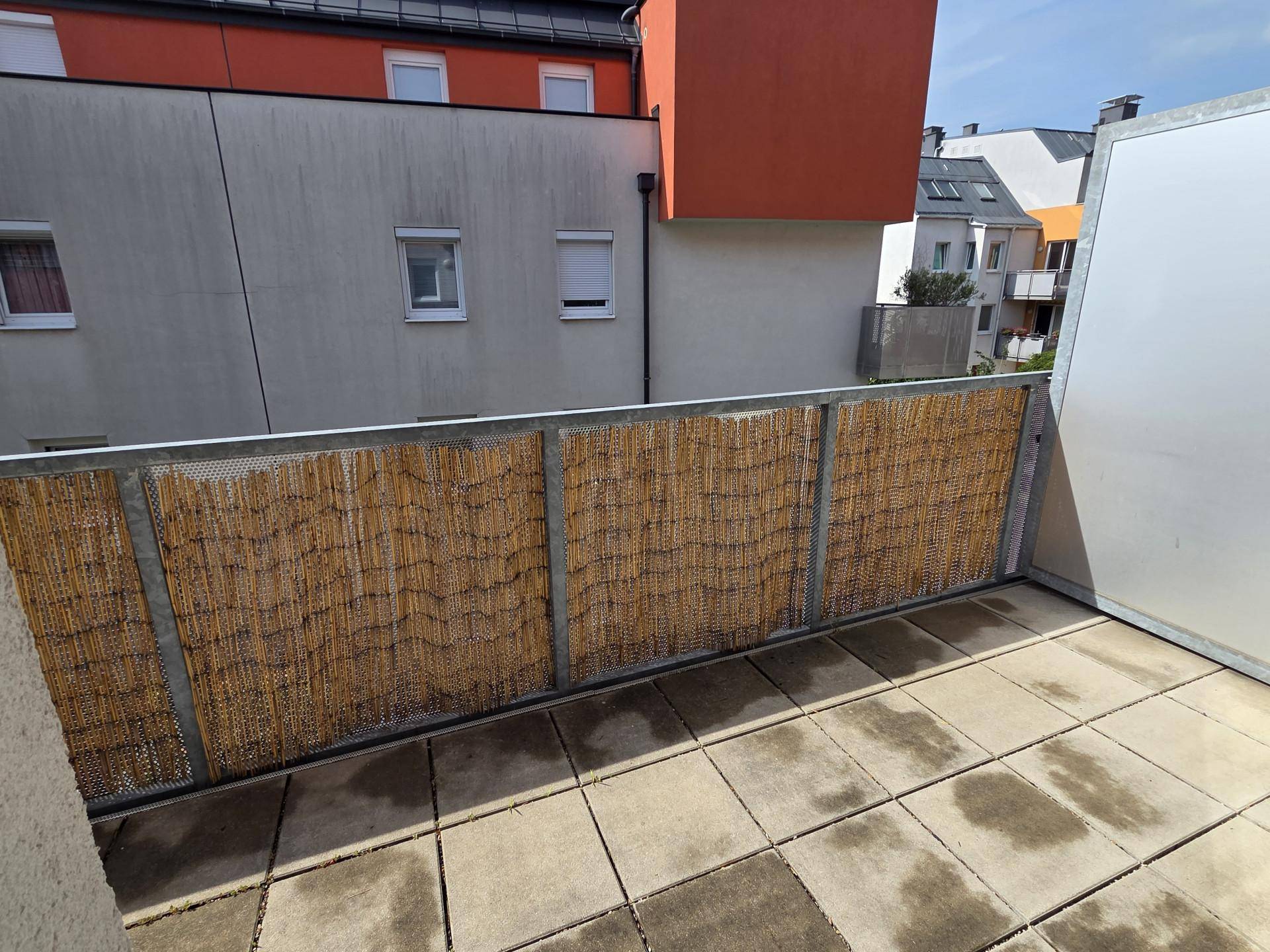 Balkon mit Fliesenboden und Bambus-Sichtschutz, bietet Privatsphäre und Blick auf die Umgebung.