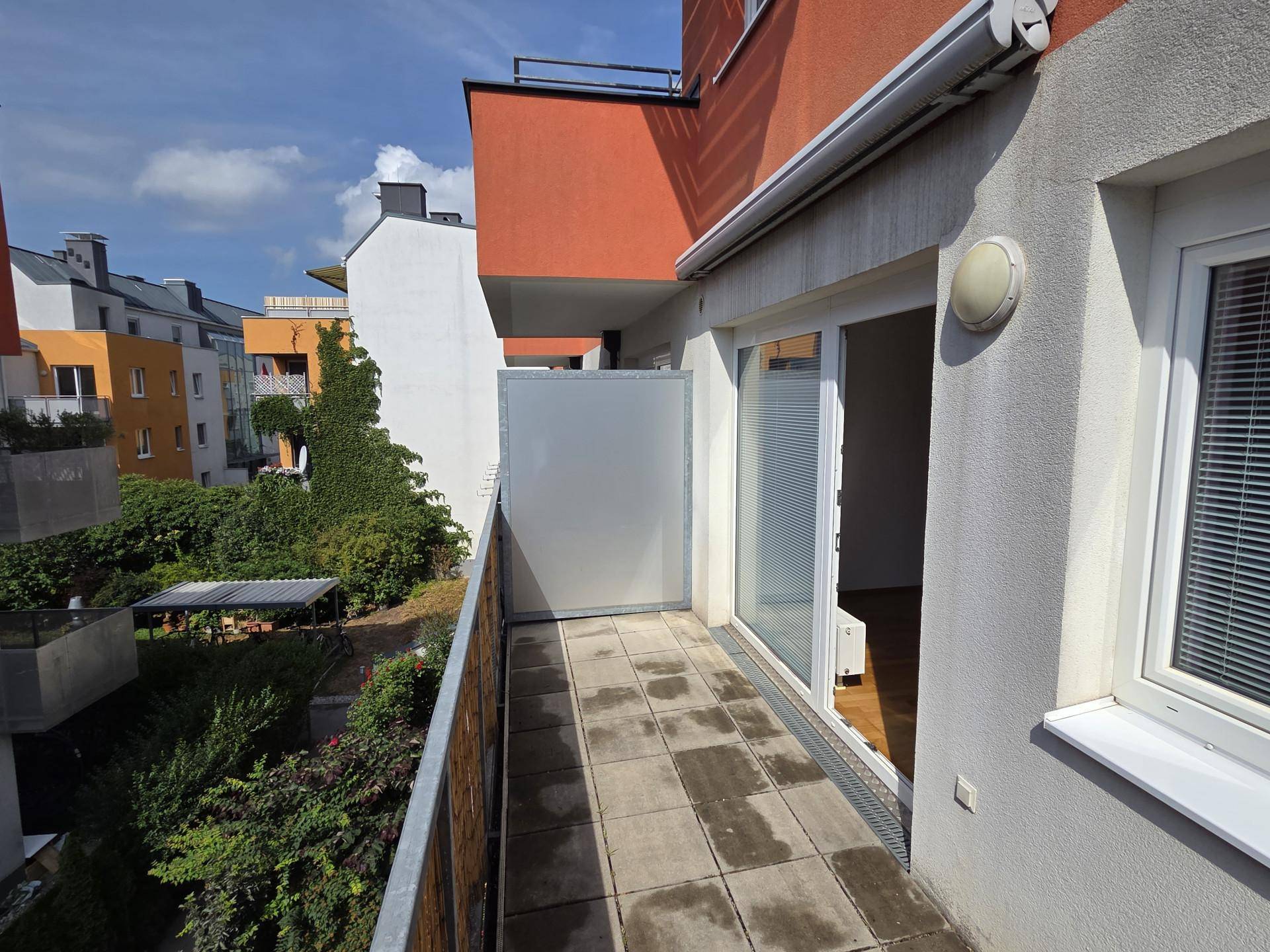 Schmaler Balkon mit Fliesenboden und Schiebetür, bietet Zugang zum Innenbereich und Ausblick.