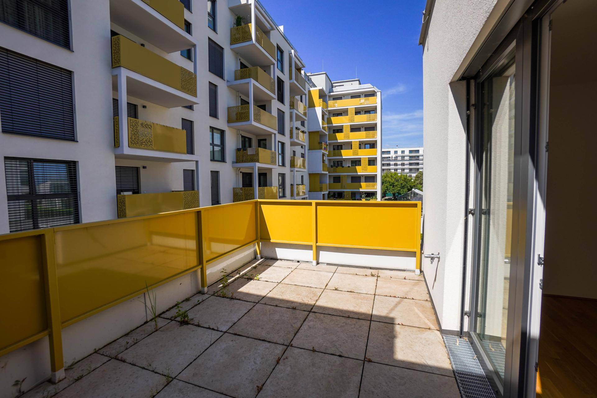 Geräumiger Balkon mit gelbem Geländer und Blick auf die umliegenden Neubauten.