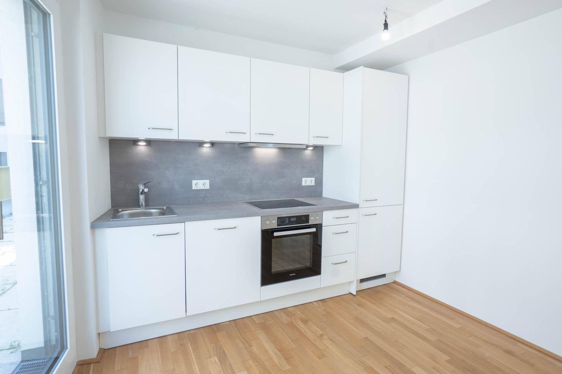 Moderne Einbauküche in Weiß mit integrierten Geräten und Holzboden.