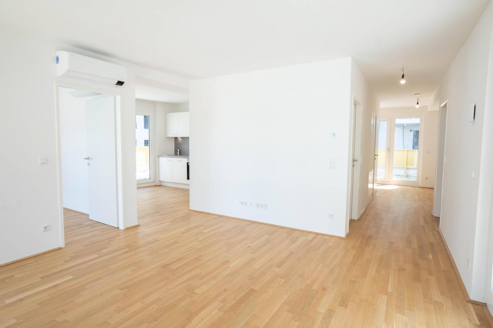 Offener Wohn- und Essbereich mit Holzboden und Blick auf die moderne Küche.