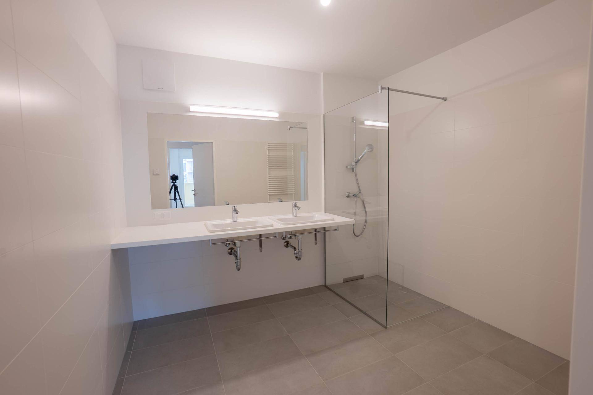 Modernes Badezimmer mit Doppelwaschbecken, großer Spiegelfläche und begehbarer Dusche.