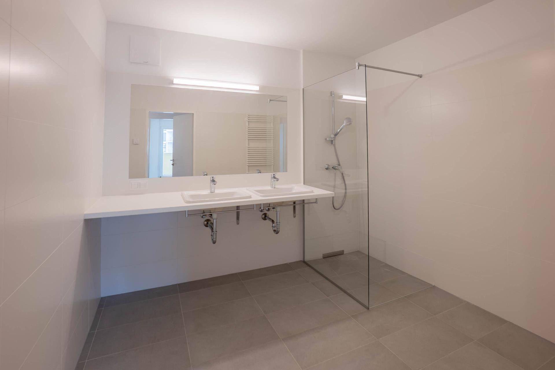 Modernes Badezimmer mit Doppelwaschbecken, großer Spiegelfläche und begehbarer Dusche.