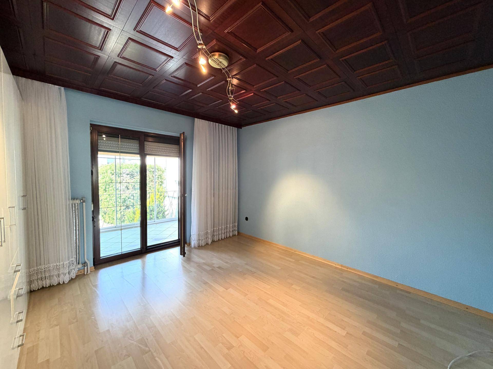 Helles Schlafzimmer mit Holzboden, blauen Wänden und Zugang zum Balkon.