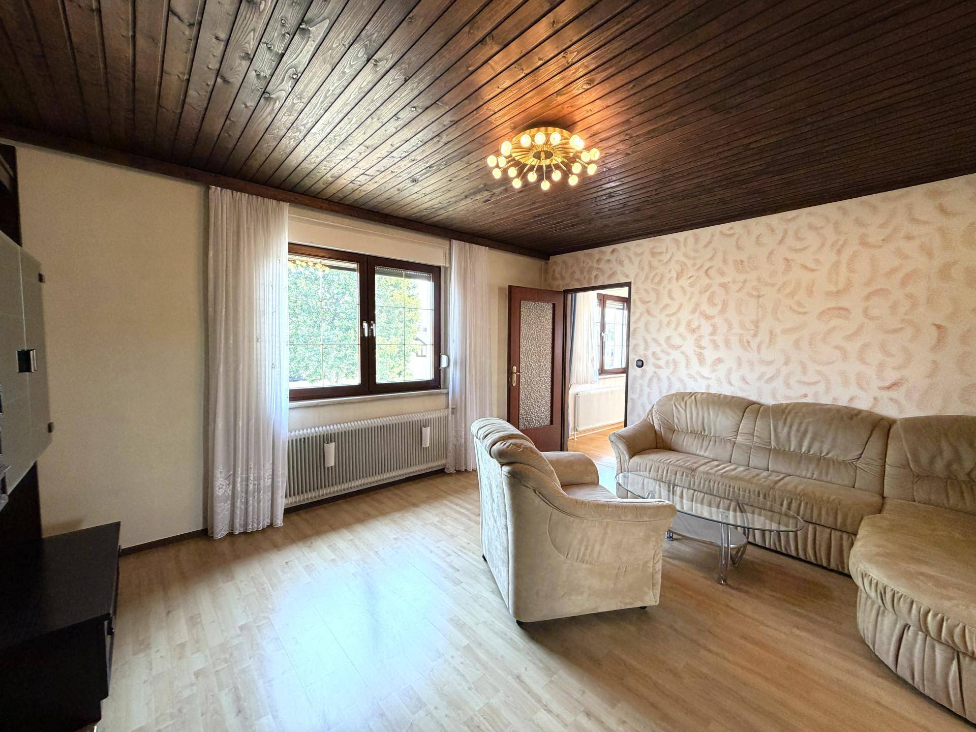 Gemütliches Wohnzimmer mit Holzboden, Holzdecke und bequemen Sofas.