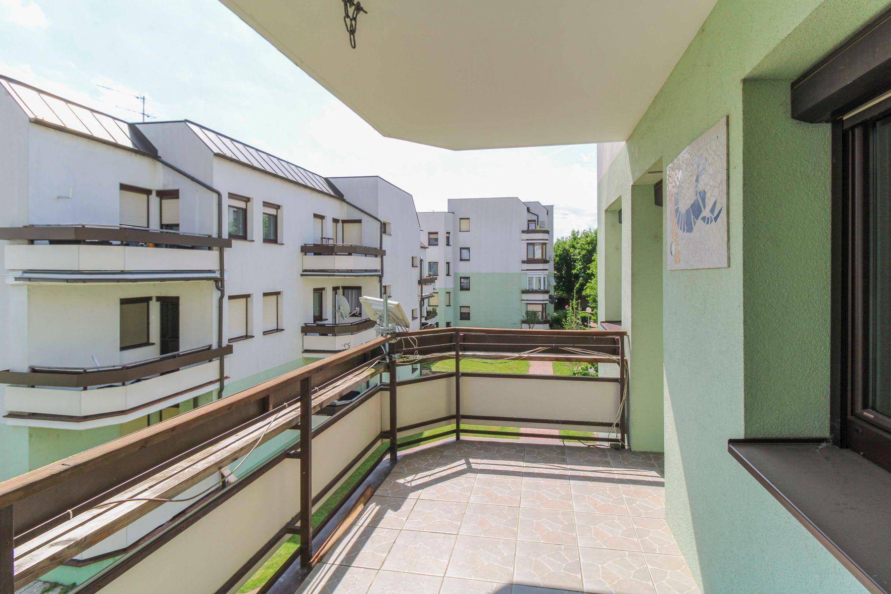 Geräumiger Balkon mit Fliesenboden und Blick auf die umliegenden Wohngebäude und Grünflächen.