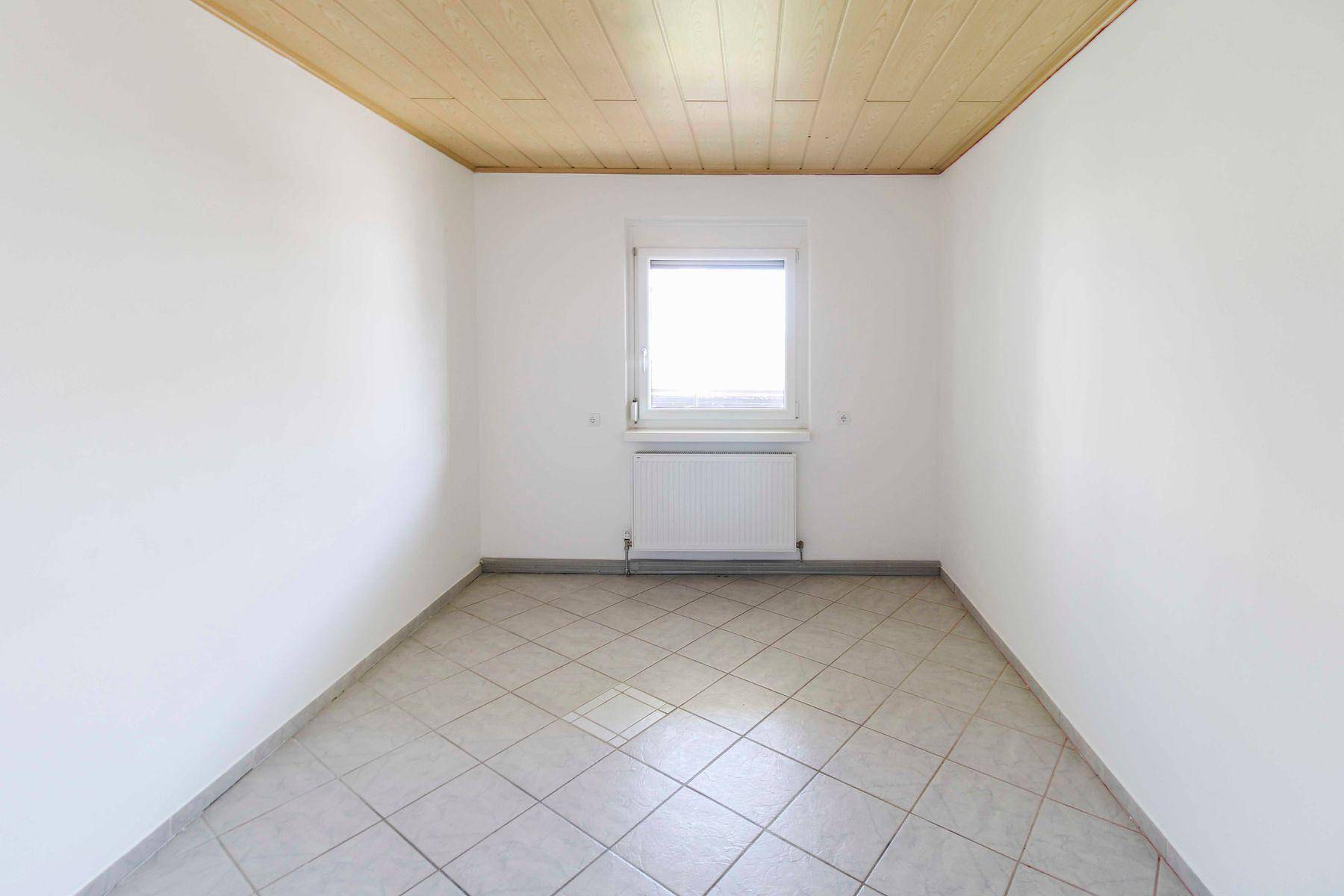 Helles Zimmer mit hellen Fliesen und einer Holzdecke, bietet eine gemütliche Atmosphäre.