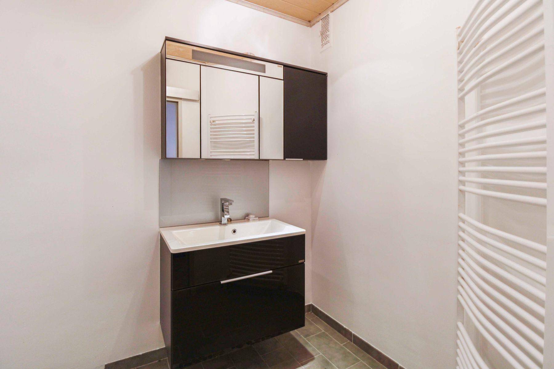 Kompaktes WC mit modernem Waschbecken, Spiegelschrank und beheiztem Handtuchhalter.