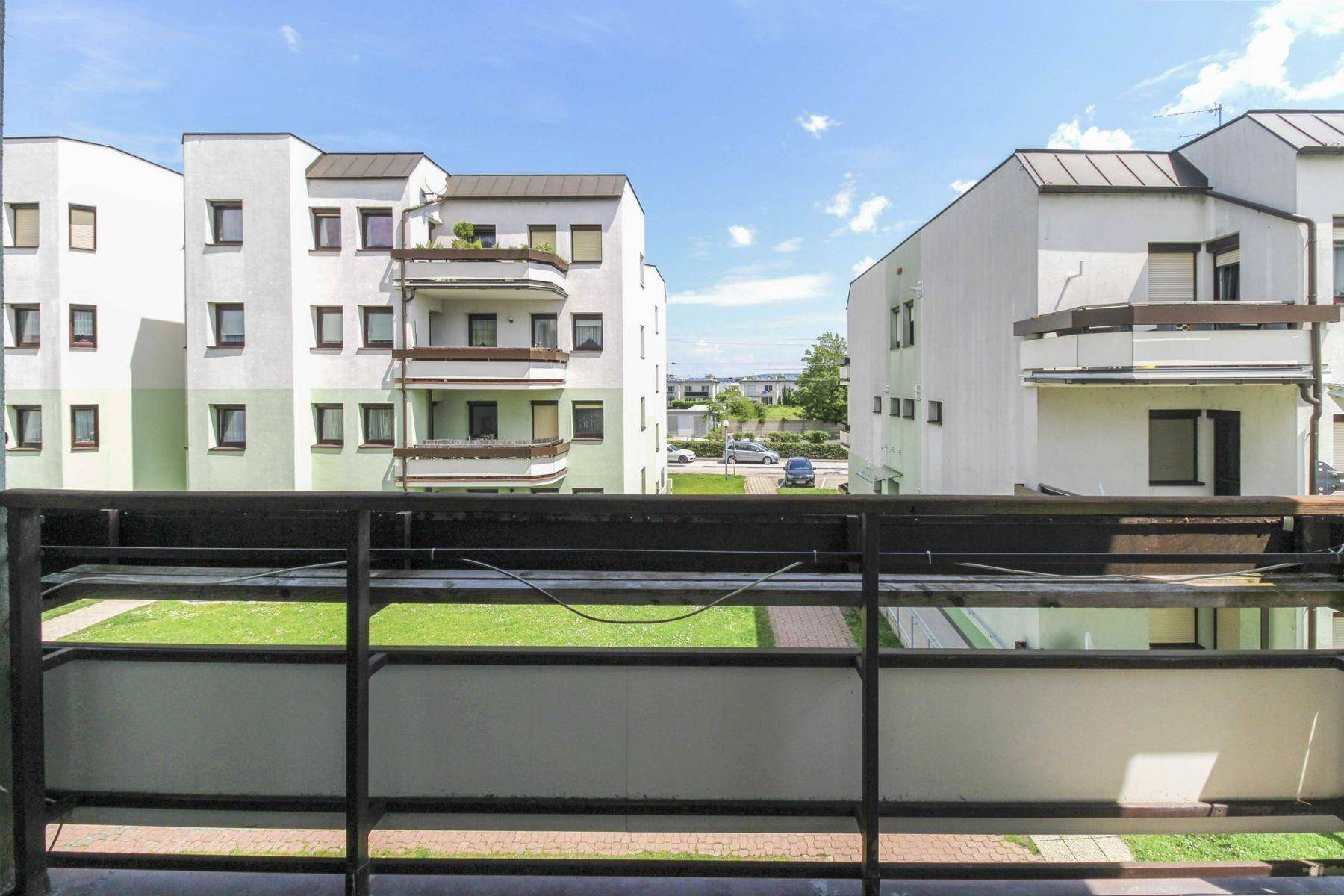 Weitblick vom Balkon über die gepflegte Grünanlage und die benachbarten Wohngebäude.